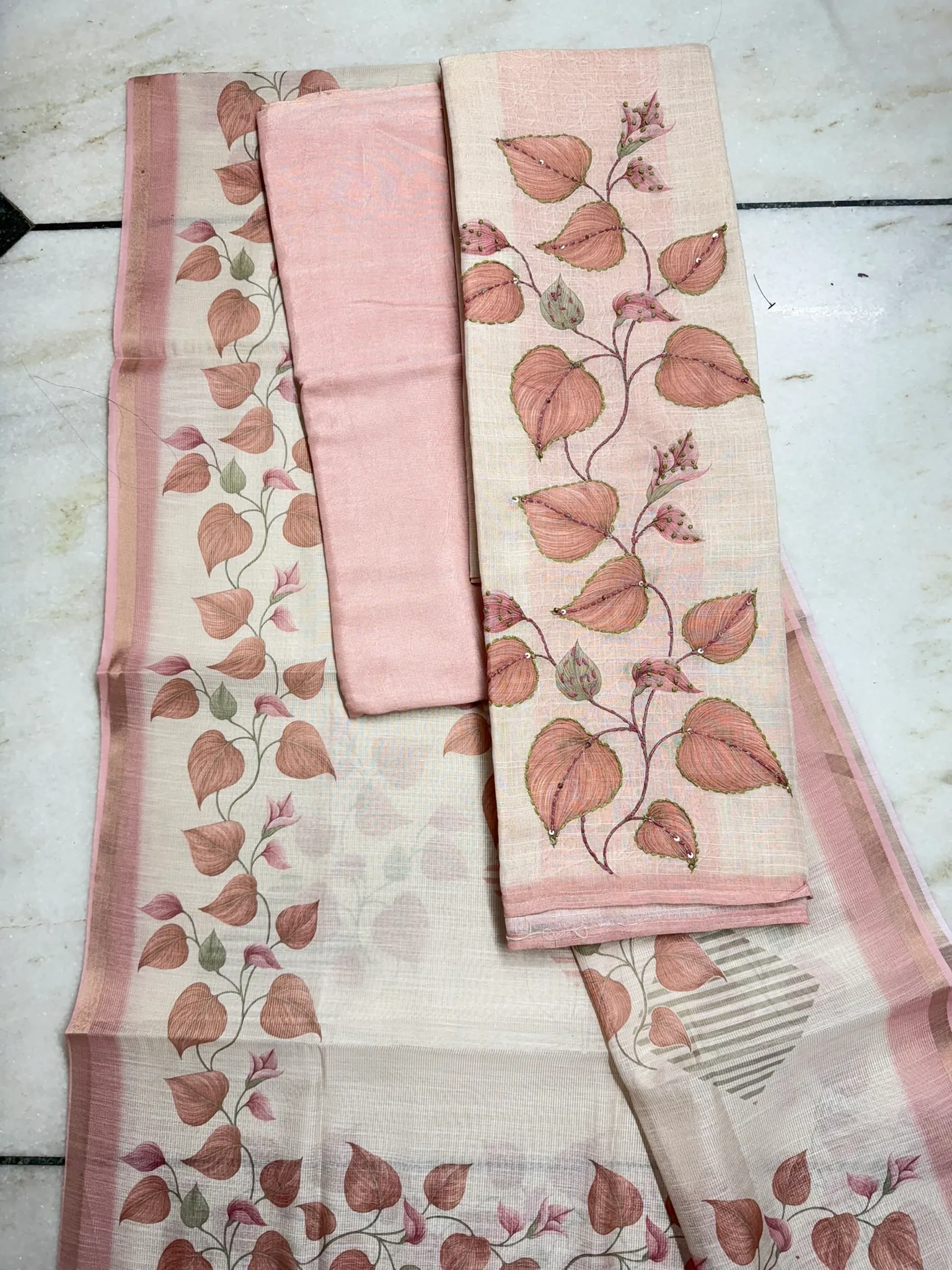 The unstitched set — the painted kurta panel, a plain blush bottom, and the leaf-printed dupatta.
