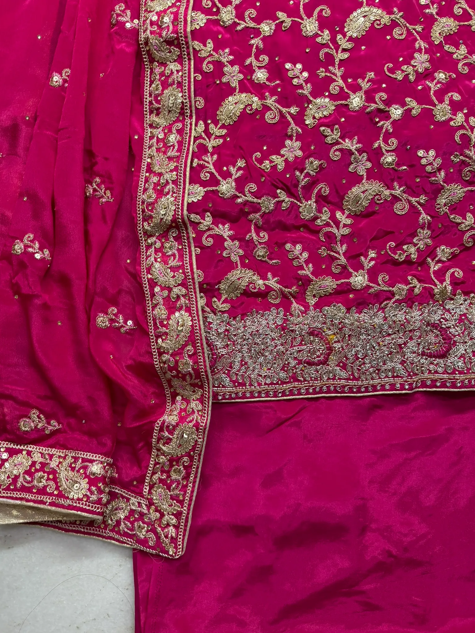 Gold zari couched vine by vine, condensing into a heavy stone-and-sequin border.
