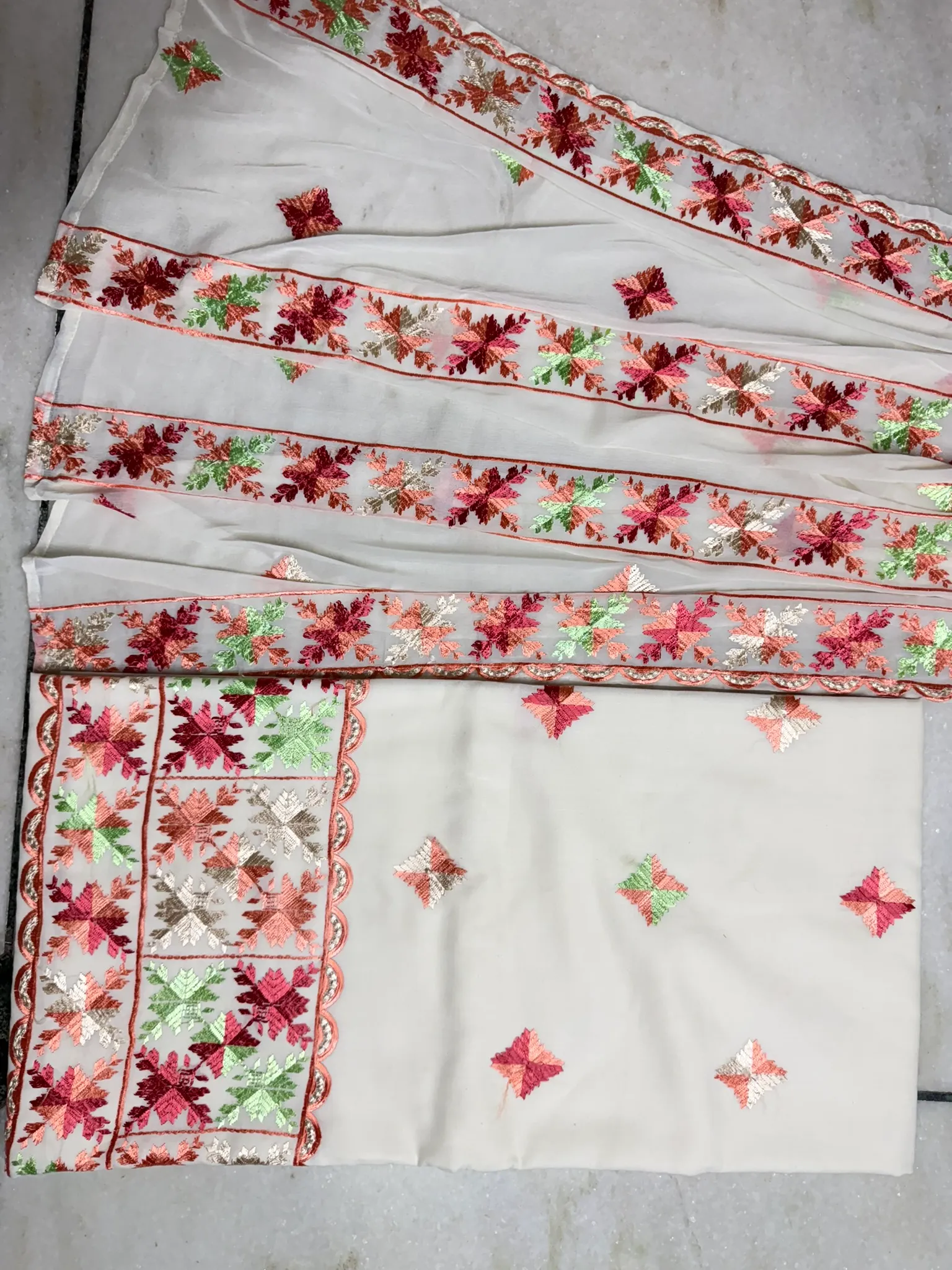 The sheer dupatta, its borders blooming the length of the fall.