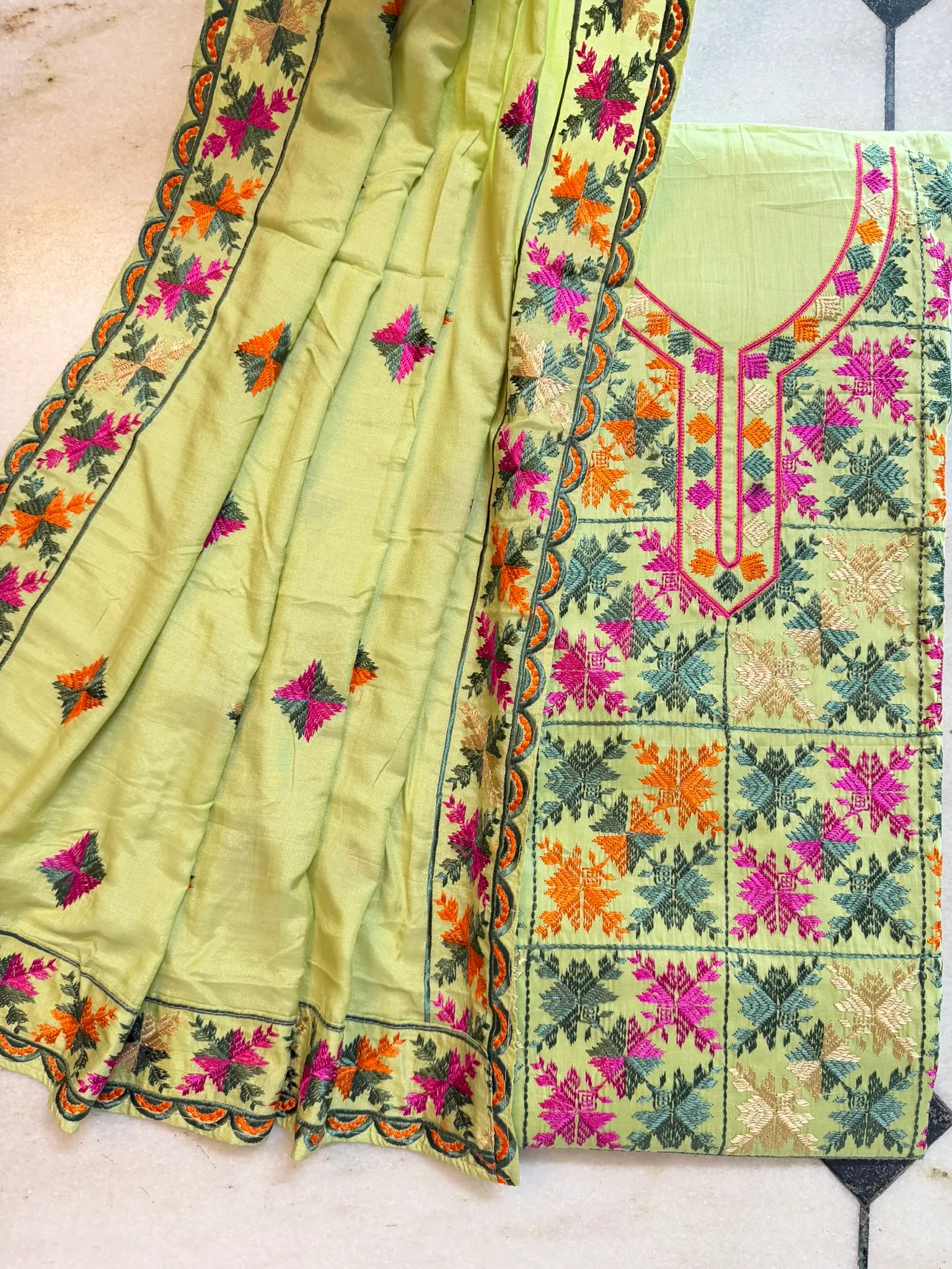 The shaded neckline placket and the chinar-leaf grid, worked square by square across the ground.
