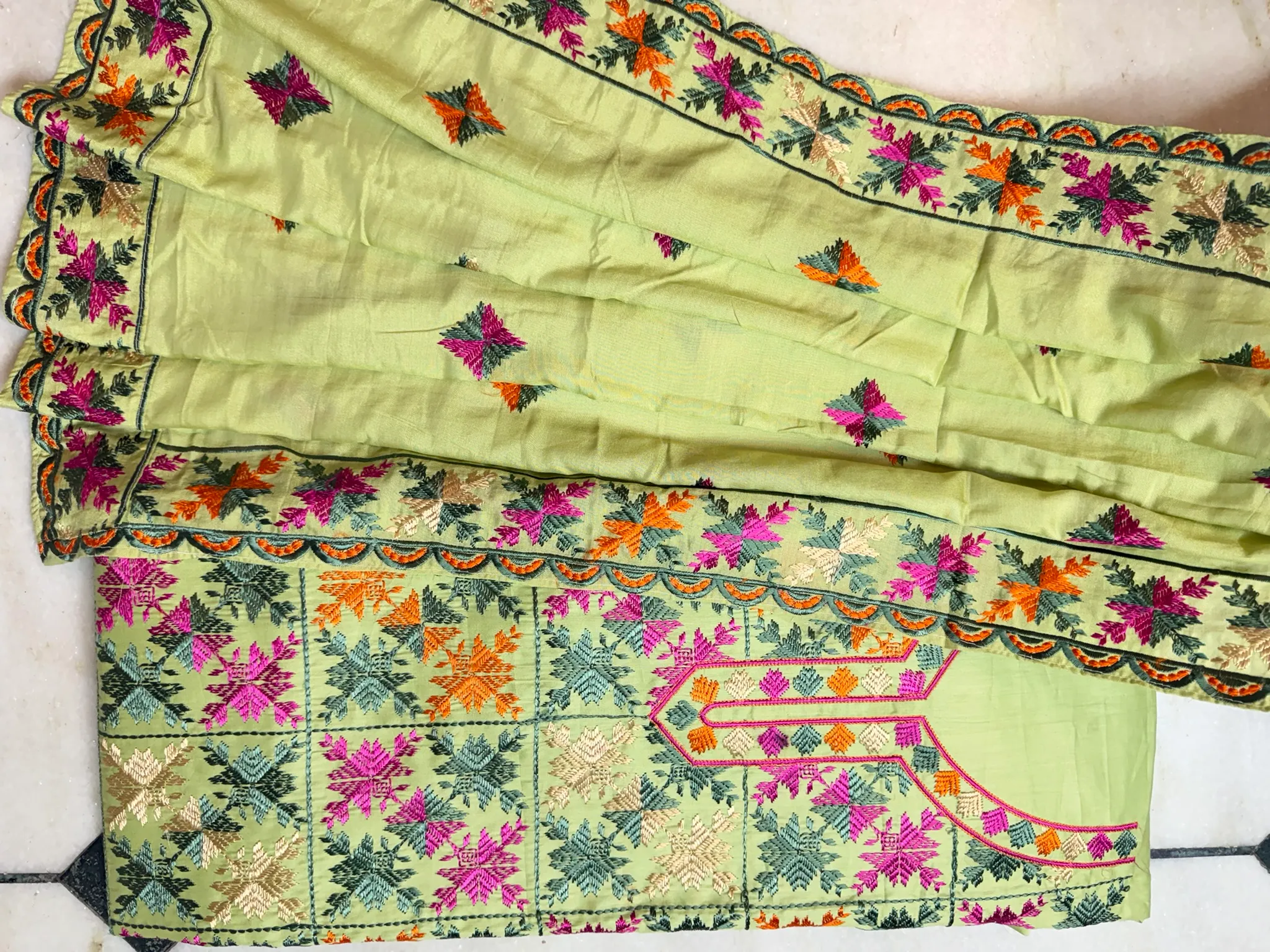 The dupatta’s scalloped border, echoing the kurta’s garden in miniature.