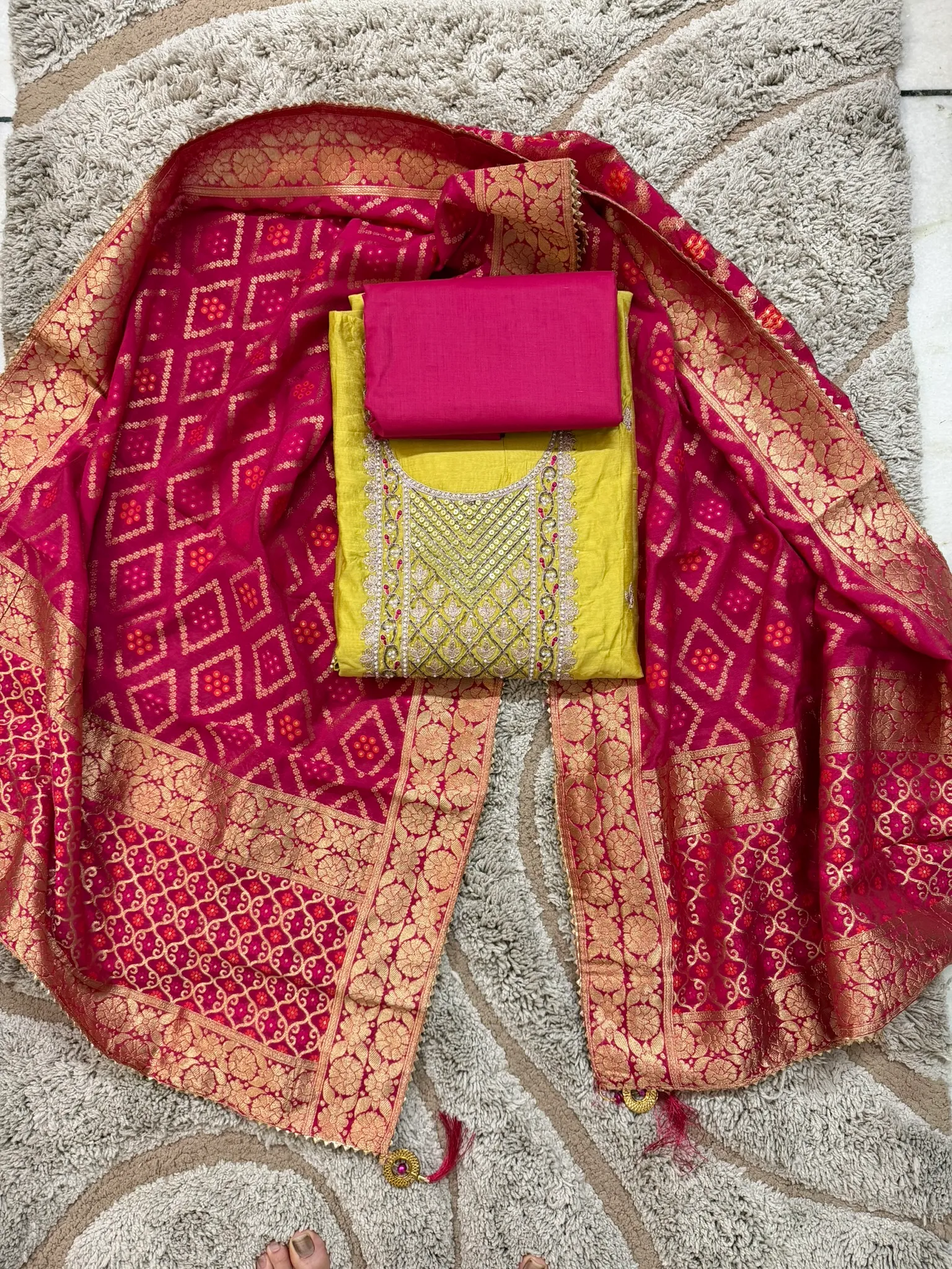 The set laid out — the yellow kurta with its jewelled yoke, a rani-pink bottom, and the bandhani-Banarasi dupatta.