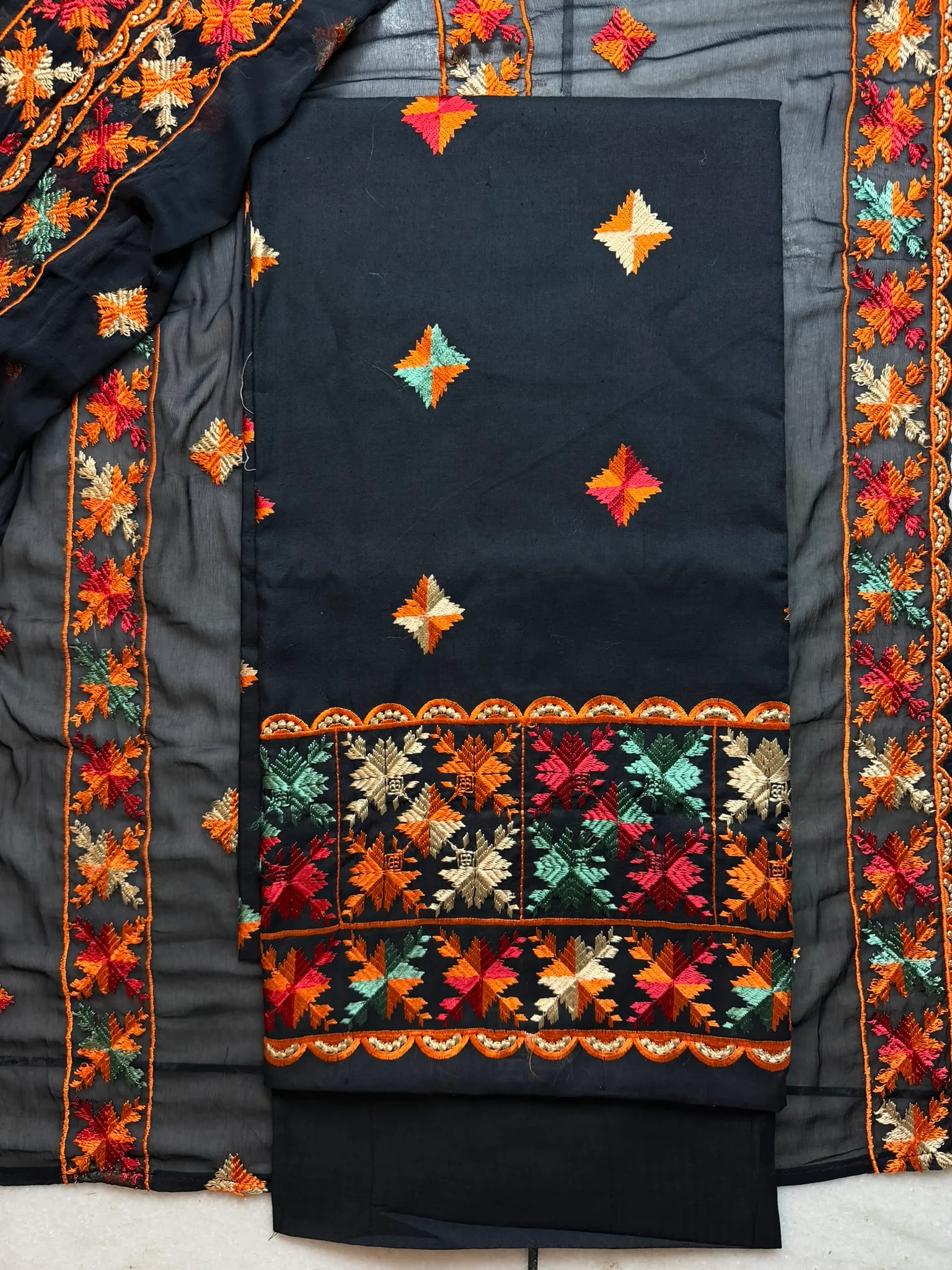 The unstitched set — kurta panel, embroidered hem and salwar, laid out as it arrives from the workshop.